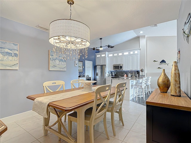 tiled dining space featuring ceiling fan with notable chandelier, lofted ceiling, and sink