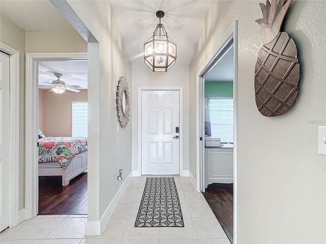 foyer featuring ceiling fan with notable chandelier and light hardwood / wood-style floors