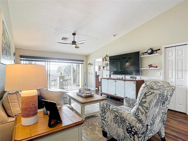 living room featuring lofted ceiling, ceiling fan, hardwood / wood-style flooring, and a textured ceiling