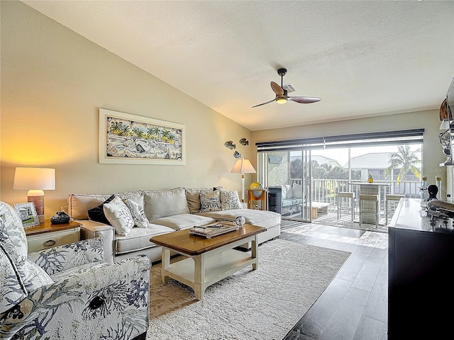 living room with ceiling fan, a textured ceiling, light hardwood / wood-style flooring, and lofted ceiling