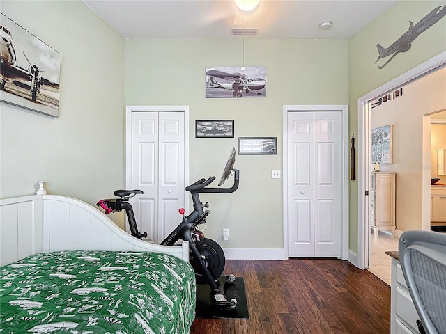 bedroom with multiple closets and dark hardwood / wood-style floors