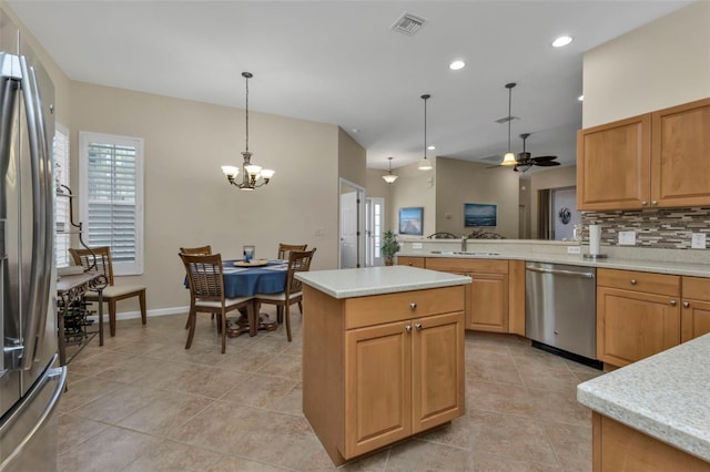 kitchen with a center island, backsplash, decorative light fixtures, ceiling fan with notable chandelier, and appliances with stainless steel finishes