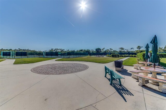 view of property's community featuring a lawn and a patio area