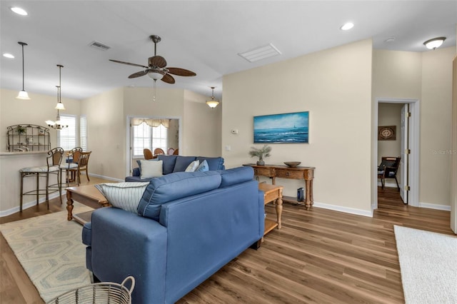 living room with hardwood / wood-style floors and ceiling fan with notable chandelier