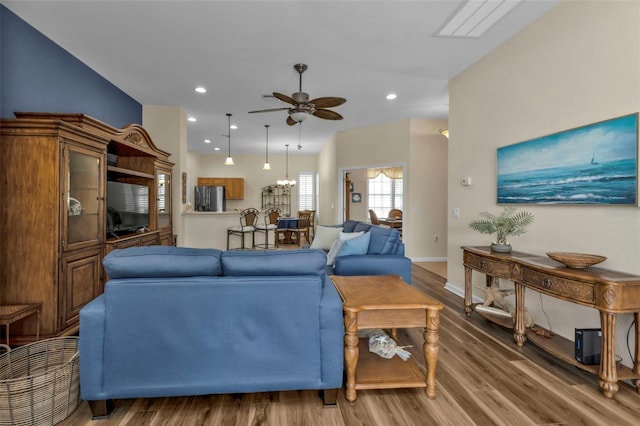 living room with ceiling fan with notable chandelier and hardwood / wood-style flooring