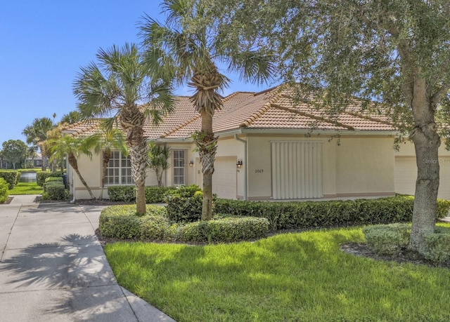 mediterranean / spanish home with stucco siding, a front lawn, concrete driveway, a garage, and a tiled roof