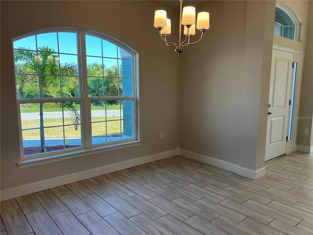 unfurnished dining area featuring plenty of natural light, a chandelier, and light wood-type flooring