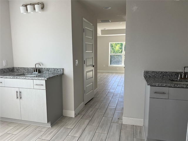 kitchen featuring white cabinetry, dark stone counters, and sink