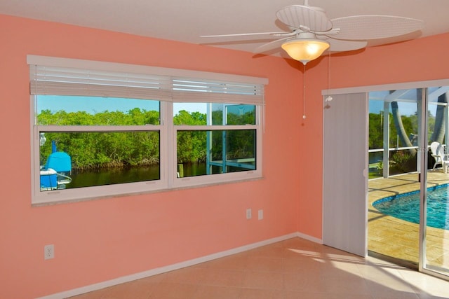 empty room with light tile patterned floors, ceiling fan, and a healthy amount of sunlight