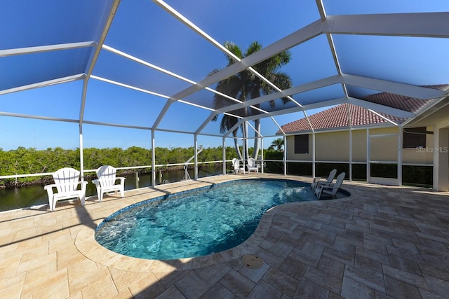 view of swimming pool featuring glass enclosure, a water view, and a patio