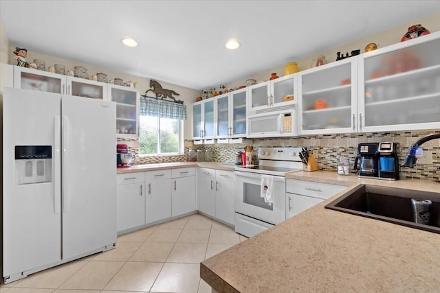 kitchen featuring white appliances, light tile patterned floors, sink, decorative backsplash, and white cabinetry