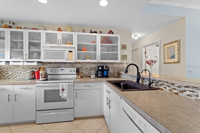 kitchen with white appliances, light tile patterned floors, backsplash, sink, and white cabinetry