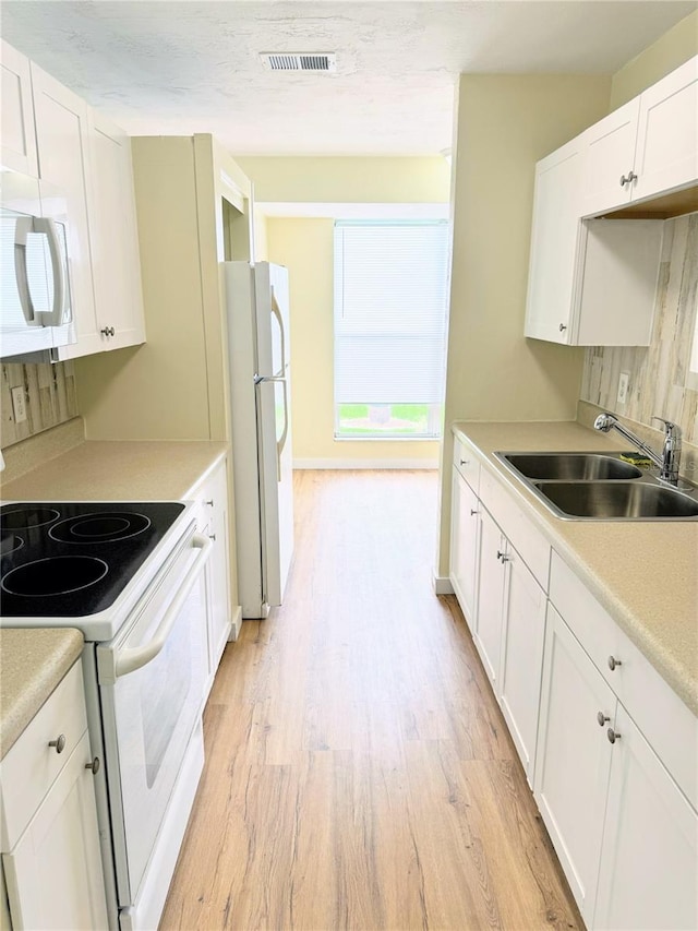 kitchen featuring white cabinets, light hardwood / wood-style flooring, white appliances, sink, and a textured ceiling