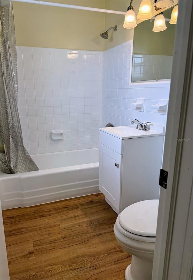 full bathroom featuring toilet, tile walls, wood-type flooring, shower / tub combo with curtain, and vanity