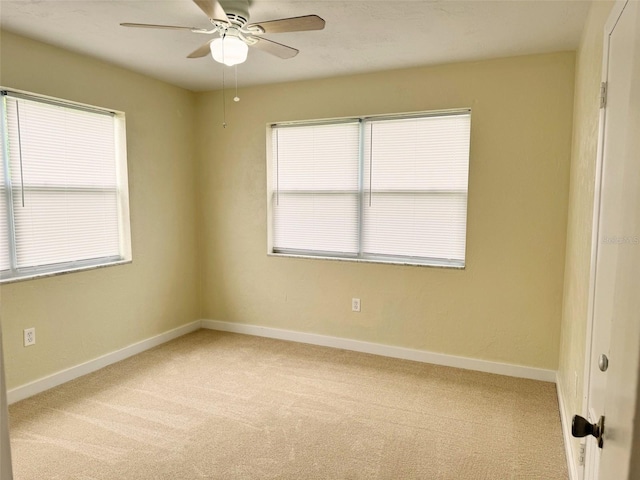 carpeted spare room featuring plenty of natural light and ceiling fan