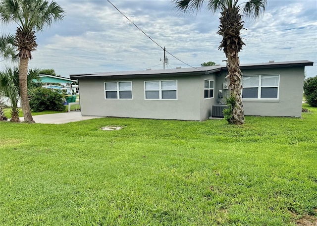 rear view of property featuring a yard and cooling unit