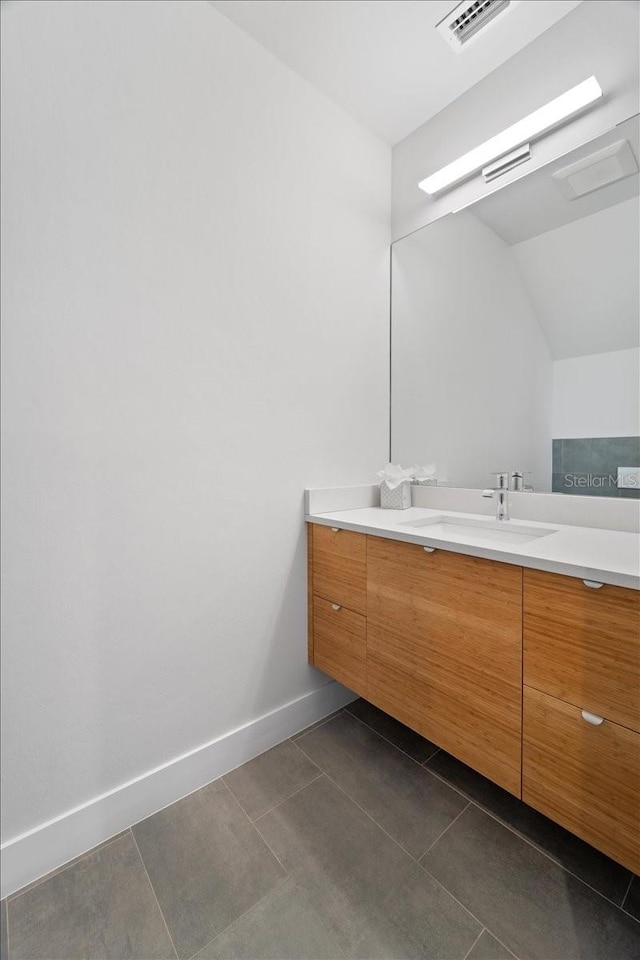 bathroom with lofted ceiling, vanity, and tile patterned flooring