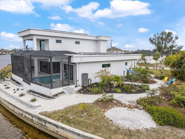 rear view of house with a water view and a lanai