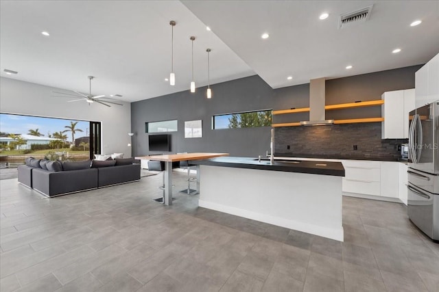 kitchen with pendant lighting, backsplash, stainless steel fridge, and white cabinets