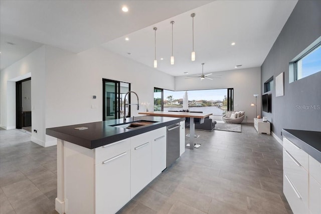 kitchen with pendant lighting, white cabinetry, an island with sink, sink, and stainless steel dishwasher