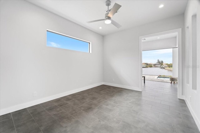 unfurnished room featuring a wealth of natural light, ceiling fan, and a water view