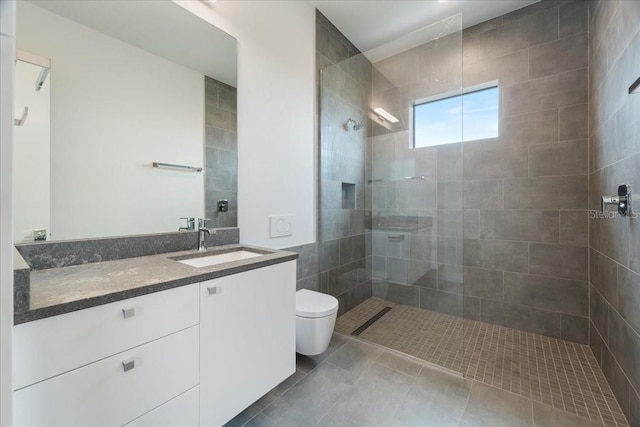 bathroom with tile patterned floors, vanity, toilet, and a tile shower