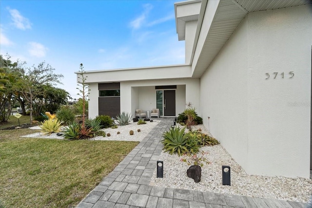 property entrance with a lawn and stucco siding