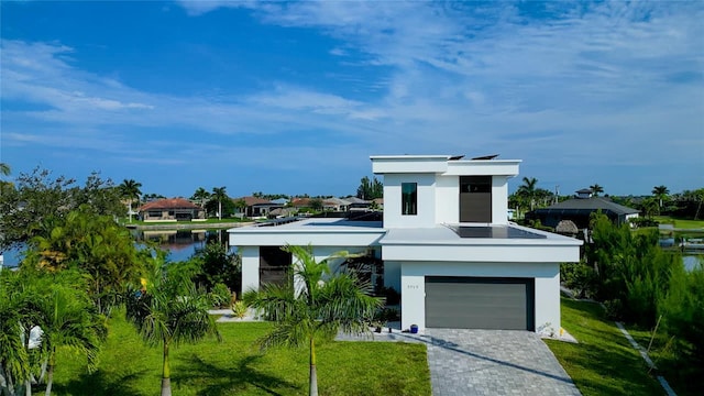 modern home with a garage, a front yard, decorative driveway, and stucco siding