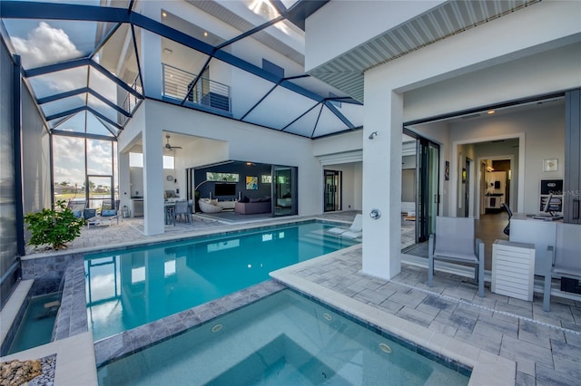 view of swimming pool featuring a pool with connected hot tub, glass enclosure, a patio, and an outdoor hangout area