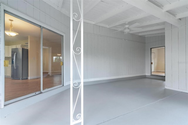 garage featuring stainless steel refrigerator with ice dispenser, ceiling fan, and wooden walls