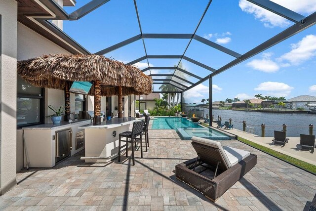 view of patio / terrace with a water view, a bar, glass enclosure, and wine cooler