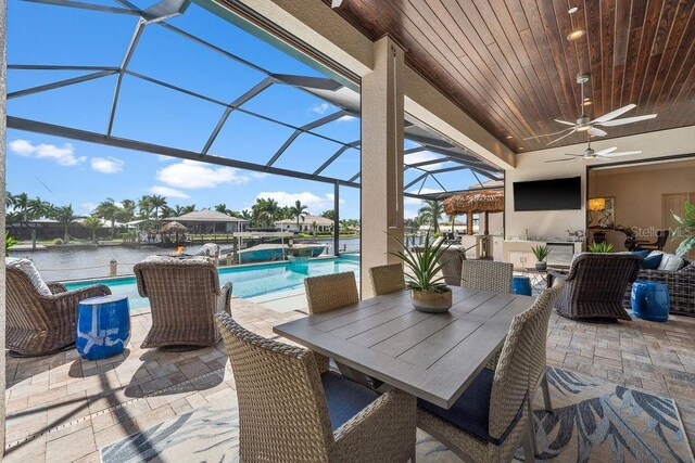 view of patio featuring a lanai, ceiling fan, and a water view