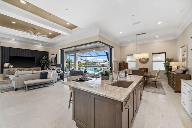 kitchen with ceiling fan with notable chandelier, hanging light fixtures, sink, white cabinetry, and light stone counters