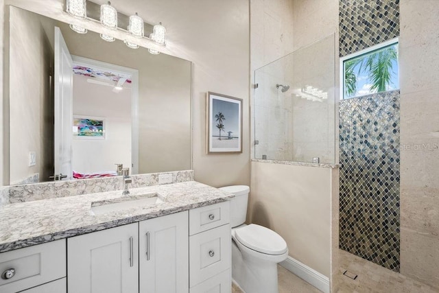 bathroom with tiled shower, vanity, and toilet