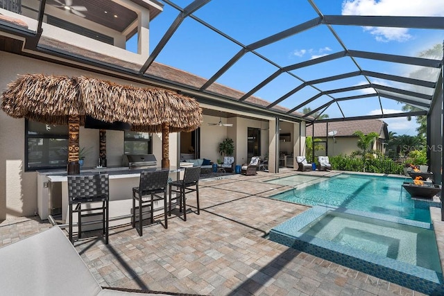 view of pool with a bar, an in ground hot tub, ceiling fan, a patio, and glass enclosure