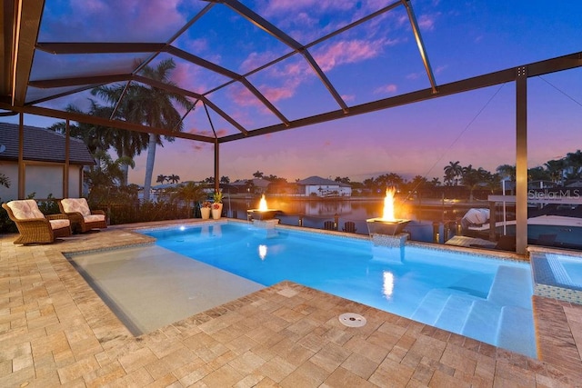 pool at dusk featuring a lanai, a patio area, and pool water feature