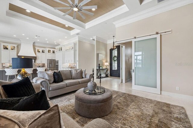 living room featuring coffered ceiling, a tray ceiling, ornamental molding, a barn door, and ceiling fan