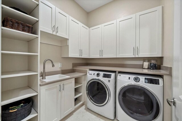 clothes washing area featuring cabinets, washer and dryer, and sink