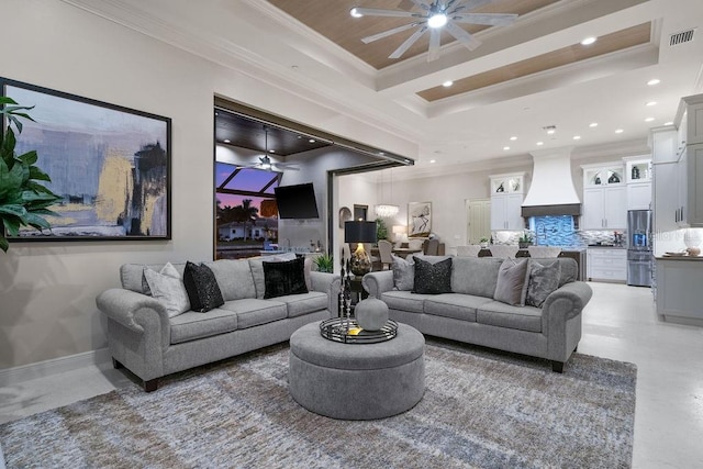 living room with concrete flooring, crown molding, ceiling fan, and a tray ceiling