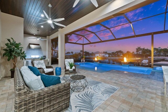 pool at dusk with pool water feature and ceiling fan