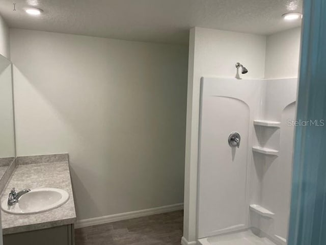 bathroom with a textured ceiling, vanity, hardwood / wood-style floors, and walk in shower