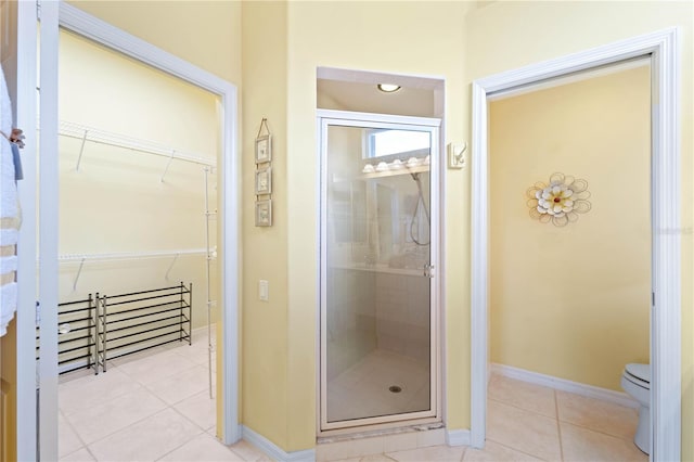 bathroom with tile patterned flooring, toilet, and a shower with shower door