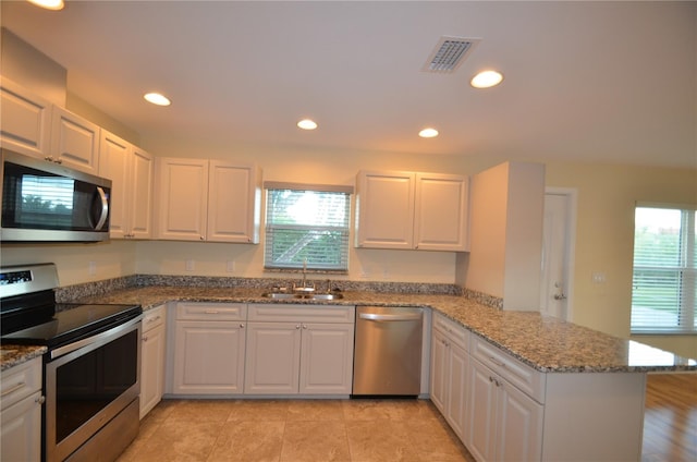 kitchen featuring white cabinets, sink, appliances with stainless steel finishes, and kitchen peninsula