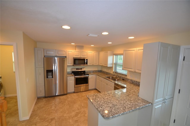 kitchen featuring white cabinets, kitchen peninsula, sink, stainless steel appliances, and light stone countertops