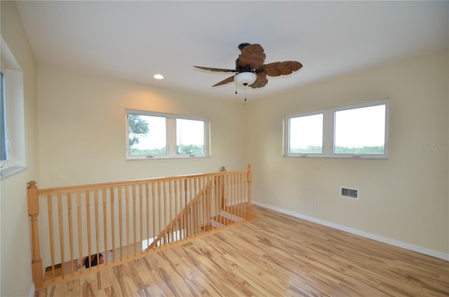 spare room with light hardwood / wood-style flooring, ceiling fan, and plenty of natural light