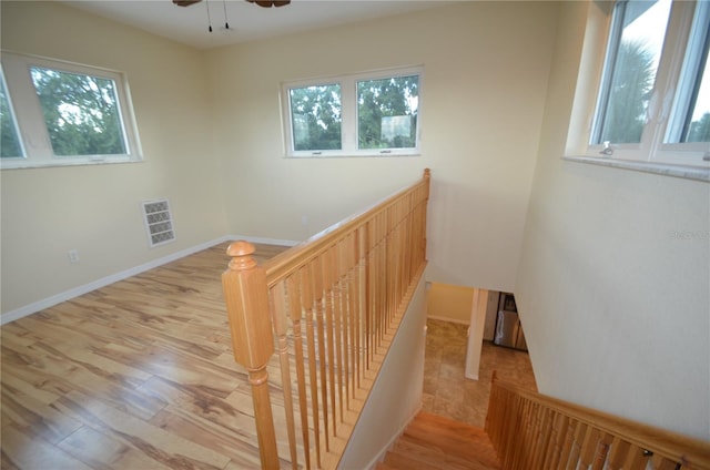 stairs featuring wood-type flooring, ceiling fan, and plenty of natural light