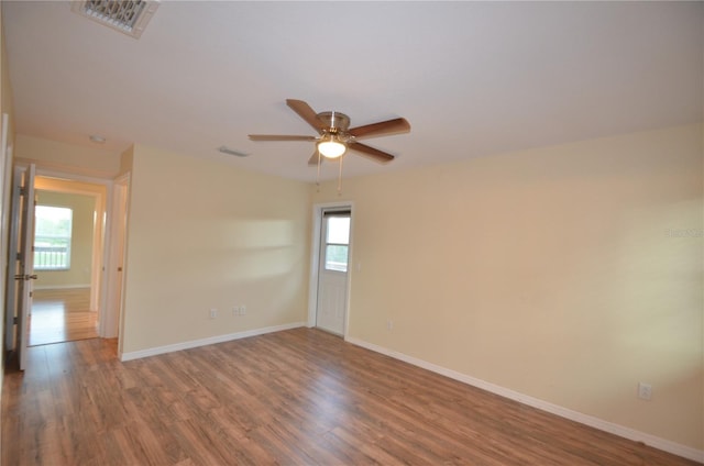 unfurnished room featuring a wealth of natural light, ceiling fan, and hardwood / wood-style floors