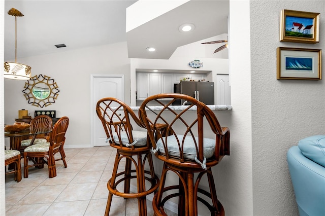 tiled dining space featuring ceiling fan and vaulted ceiling