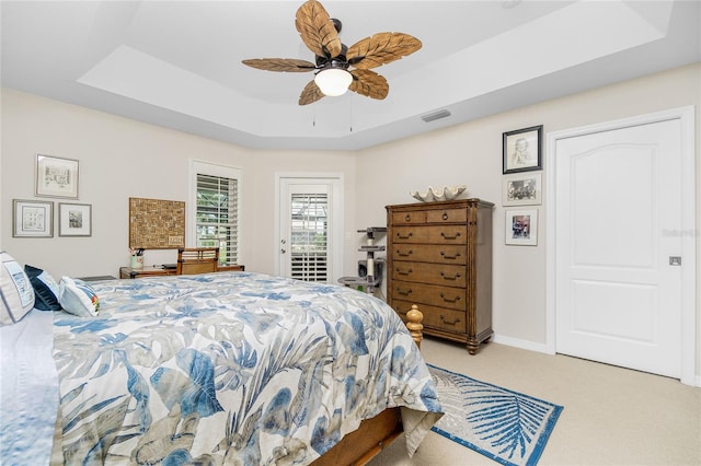 carpeted bedroom featuring ceiling fan, a raised ceiling, and access to exterior