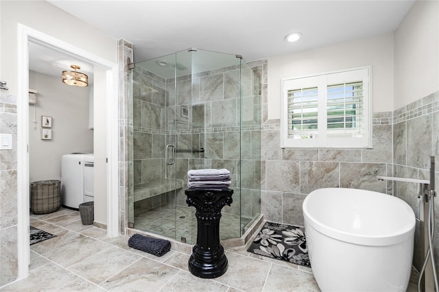 bathroom featuring plus walk in shower, tile walls, and washer / clothes dryer